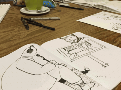 An image of sketchbooks with drawings in them open on a table.